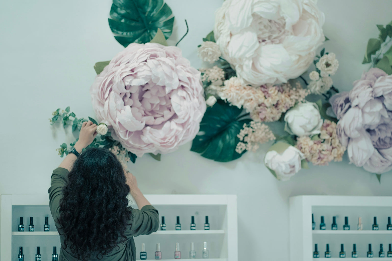 a woman is arranging flowers on a wall