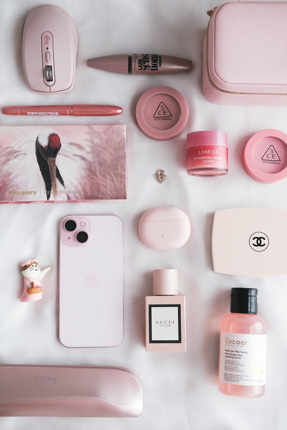 The contents of a pink purse laid out on a bed