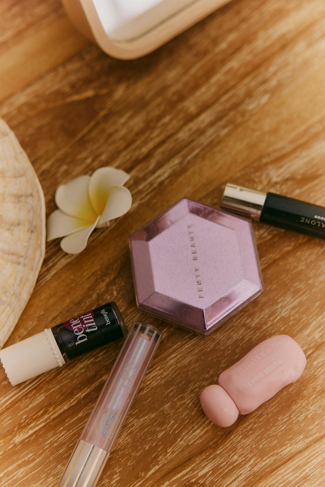 Beauty products and plumeria flower on wooden surface