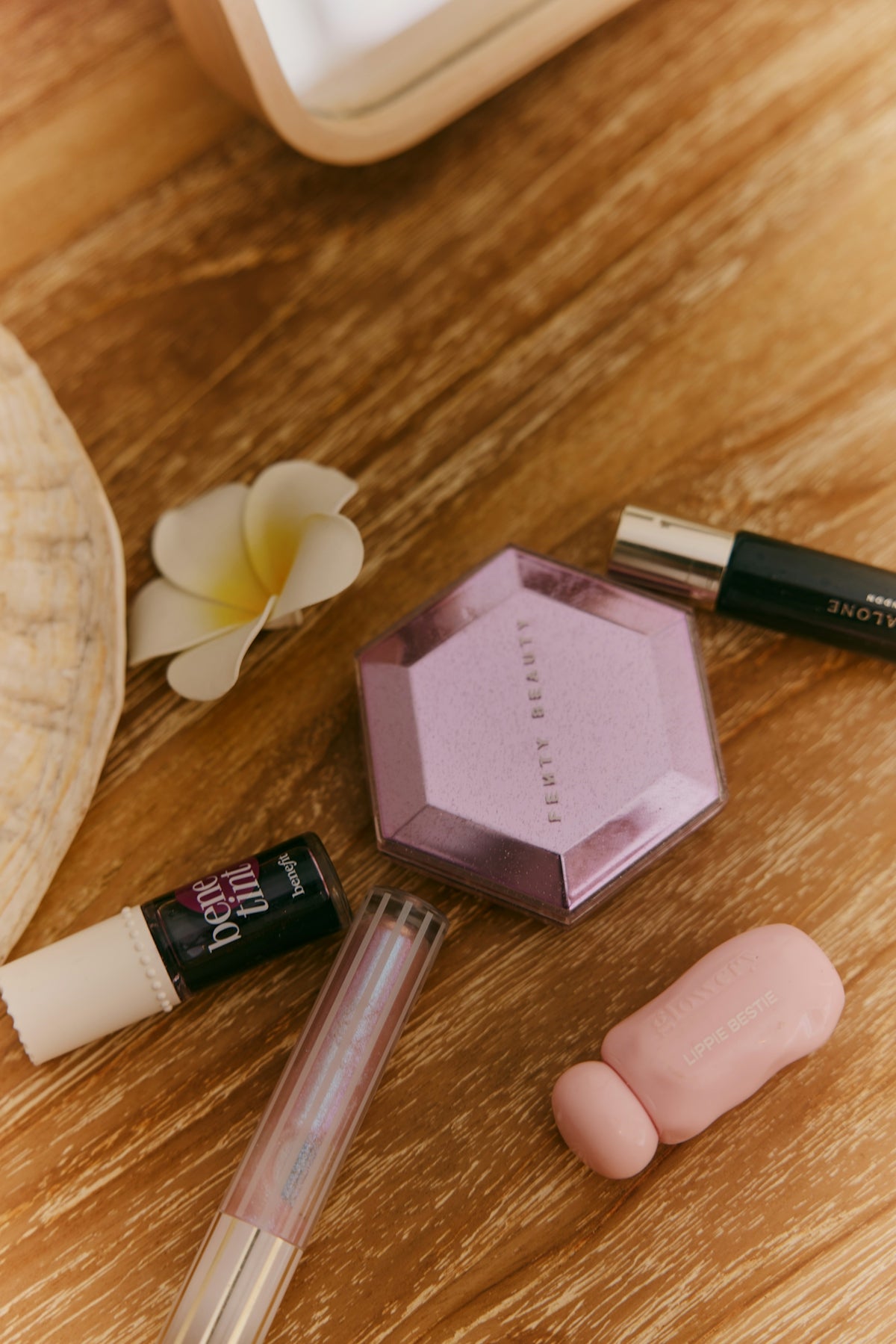Beauty products and plumeria flower on wooden surface